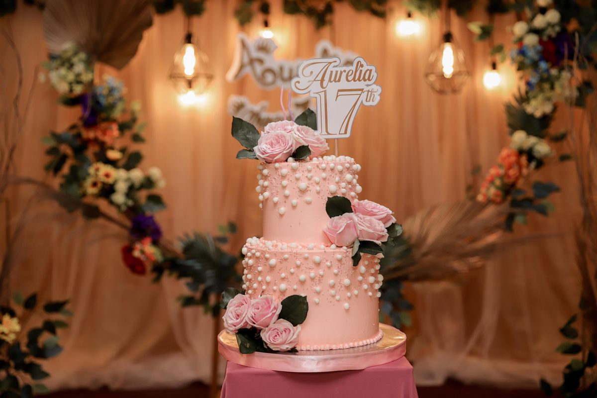 Torta rosada de dos pisos decorada con rosas y perlas